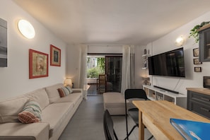 A compact living space with a sofa, a dining table, a TV, and a sliding door leading to an outdoor area. - Punta Debij Apartment Andrea, Punat, Croatia (Punat)