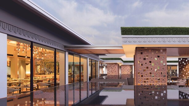 A modern hotel exterior with a reflective pool, glass doors, and outdoor seating.