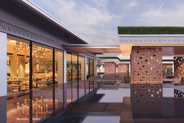 Un hôtel moderne avec une façade élégante, une piscine aux reflets scintillants, des portes en verre et des espaces de détente en plein air.