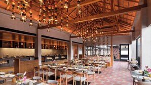 A spacious restaurant with a high ceiling, hanging light fixtures, and a checkered floor pattern.