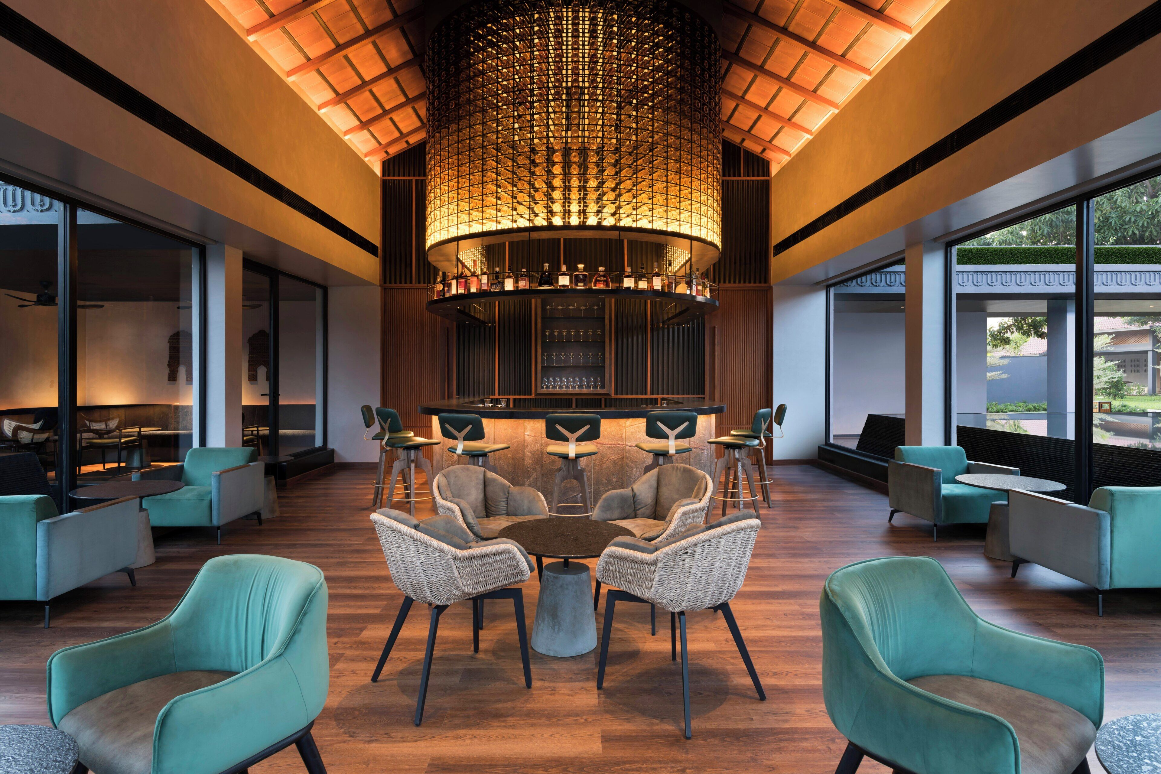 A modern interior with a central round table surrounded by chairs, a bar area, and large windows.
