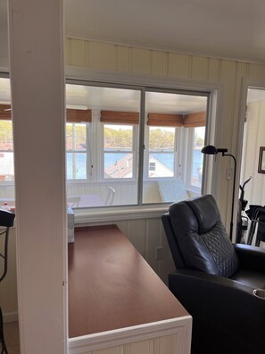 Una habitación con vista al mar, un escritorio, una silla y una lámpara.