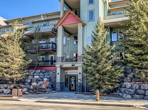 A multi-story hotel with a stone facade, balconies, and a red roof. - Charming Alpine Penthouse [Heated Pool & Hot Tubs] (Canmore)