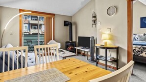 Una habitación acogedora con una mesa de comedor, sillas, televisor, chimenea y una cama con colcha estampada.