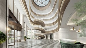 Ein modernes Interieur mit einer zentralen Wendeltreppe, großen Fenstern und einer Marmor-Rezeption.
