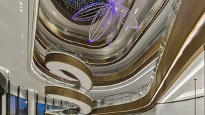 Ein modernes Interieur mit einer zentralen Wendeltreppe, mehreren Ebenen und einer dekorativen Deckenleuchte.