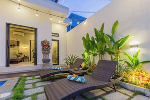 A modern outdoor lounge area with wicker chairs, a decorative elephant statue, and lush tropical plants. - Vinyak Villa (Kerobokan)