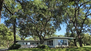 A two-story house with a covered porch, surrounded by large trees and a well-maintained lawn.