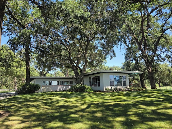 A two-story house with a covered porch, surrounded by large trees and a well-maintained lawn.