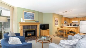 A living room with a fireplace, a television, and a dining area with wooden furniture.
