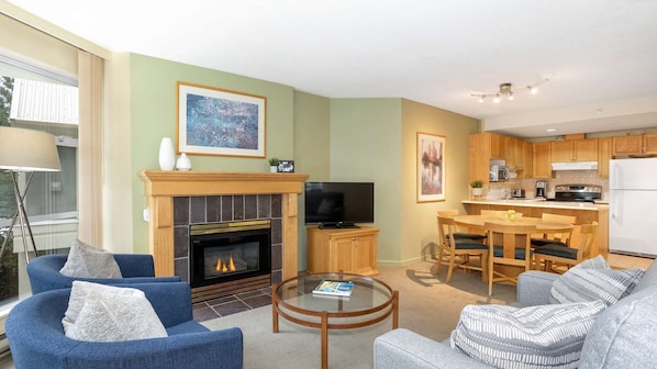 A living room with a fireplace, a television, and a dining area with wooden furniture.