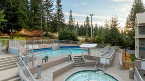 A swimming pool with steps leading down to it, surrounded by a fence and trees.