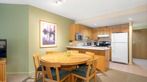 A compact kitchen with wooden cabinets, a microwave, a stove, and a refrigerator.