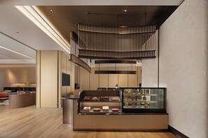A modern hotel lobby with a central counter, a seating area, and a staircase. - Hilton Garden Inn Harbin Haxi (Harbin)