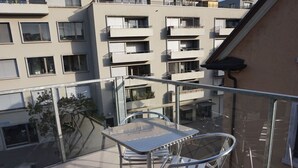 A balcony with a table and chairs, overlooking a residential area with multiple buildings. - Apartment  by Interhome (Zurich)