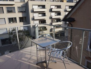 Ein Balkon mit Tisch und Stühlen, mit Blick auf eine Wohngegend und mehrere Gebäude.