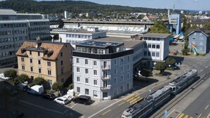 A modern urban street with tram lines, buildings, and a clear view of the surrounding area. - Apartment  by Interhome (Zurich)