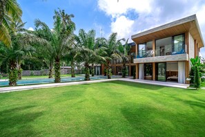 Una casa moderna con piscina, ventanas amplias y un césped bien cuidado.