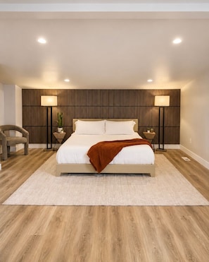 A bedroom with a bed, two bedside tables, a chair, and a wall-mounted panel. - Modern and Cozy Retreat (Pleasant Grove)