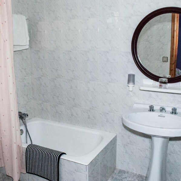 A bathroom with a bathtub, a sink, and a mirror. - Hotel Alto de las Estazadas (Cabrales)