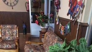 A living room with patterned furniture, a potted plant, and a wall clock. - Hotel Alto de las Estazadas (Cabrales)