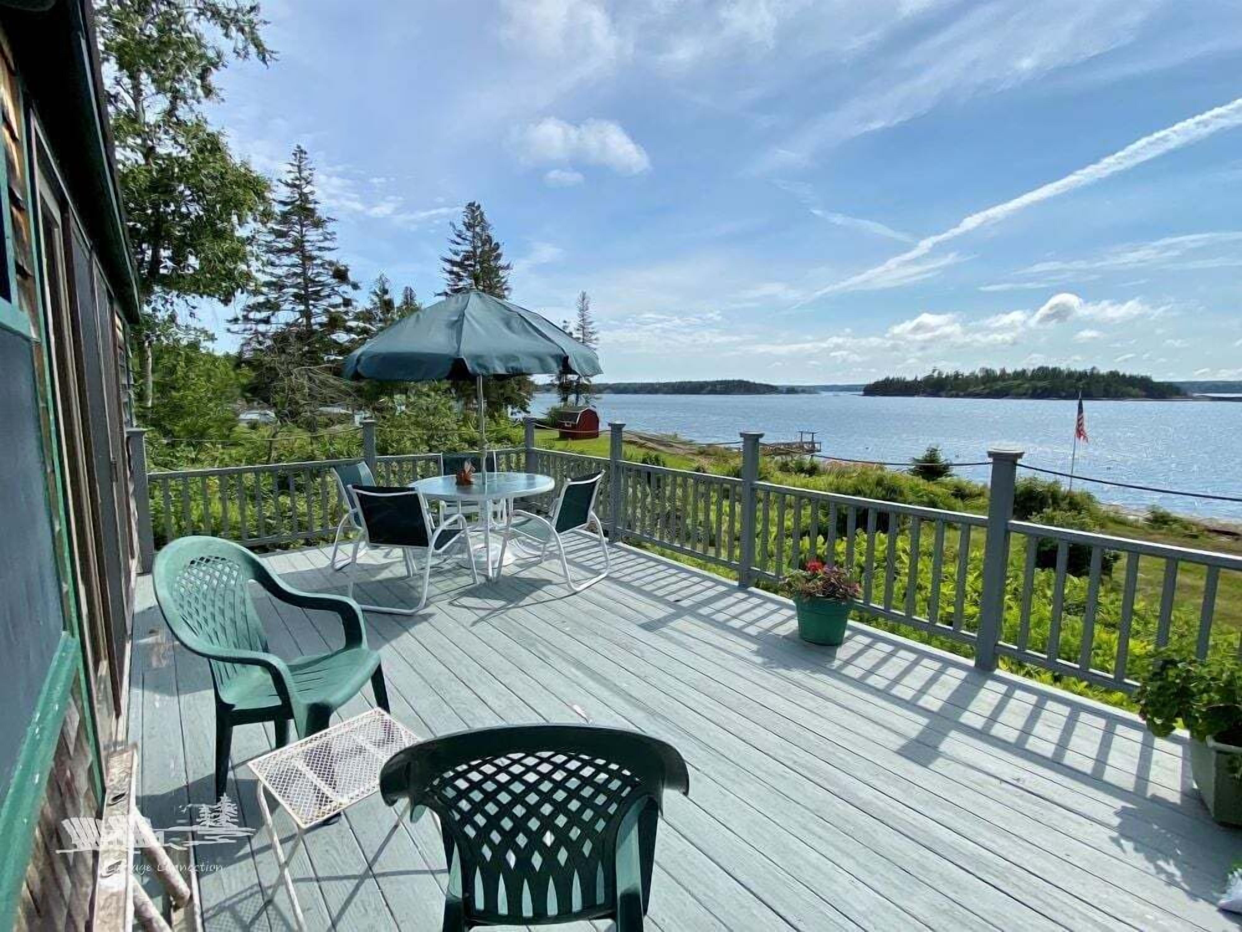 Een terras met buitenmeubilair, uitzicht op water en een vlag.