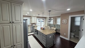 A spacious kitchen with white cabinetry, a granite island, and a dining area with chairs. -  4 bedroom + bonus room house  with ocean view in Sea Isle City (Sea Isle City)