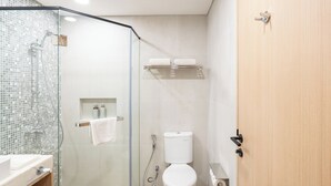 Ett modernt badrum med en dusch som är avskärmad med glasväggar, en toalett och ett handfat.