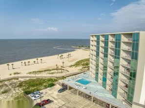 A hotel with a pool, beach view, and a parking area. - Sea Breeze Beachfront Walkout Poolside Condo (Biloxi)