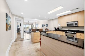 A modern kitchen with wooden cabinets, stainless steel appliances, and a large island. - Sea Breeze Beachfront Walkout Poolside Condo (Biloxi)