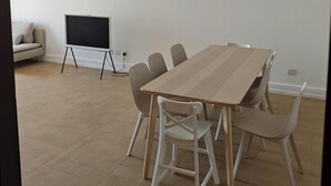 Uma sala de conferências com uma mesa de madeira, seis cadeiras, um quadro branco e um sofá.