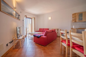 Ein Wohnzimmer mit einem roten Sofa, Holzstühlen, einem Glastisch und einem Bild an der Wand.