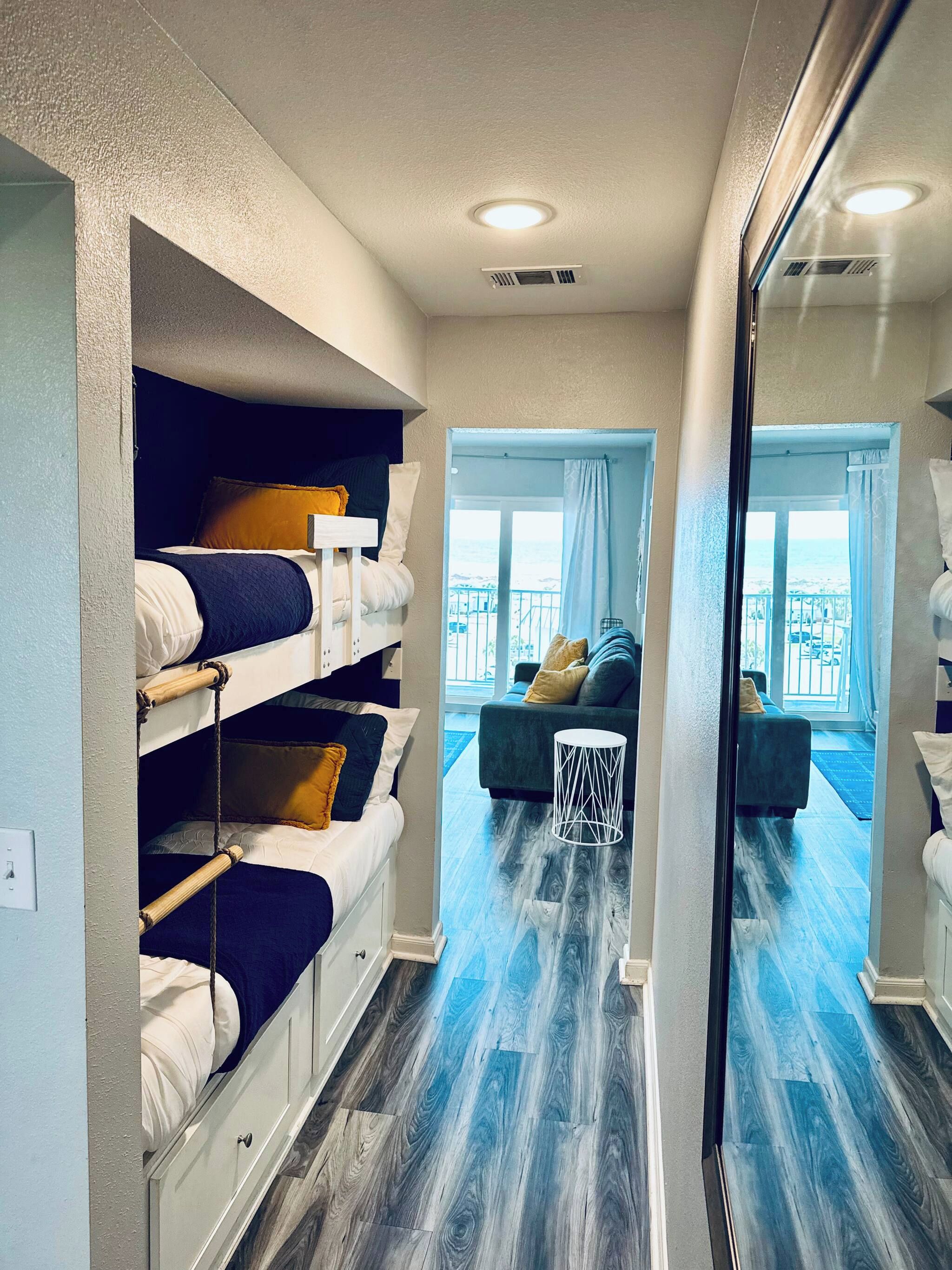 Une chambre avec des lits superposés, un canapé, une petite table et une vue sur l’océan.