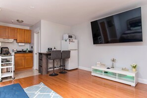 Una cocina moderna con armarios de madera, un refrigerador blanco y una barra con dos taburetes.