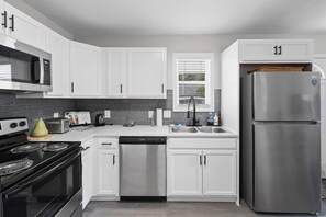 A modern kitchen with white cabinets, a stainless steel refrigerator, a microwave, a stove, and a dishwasher. - 7 Min Walk to Golden Belt | 8 Min to Hospital (Durham)
