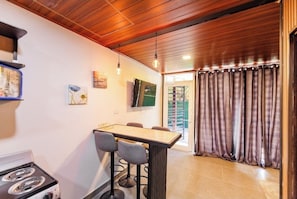 A kitchen with a stove, bar stools, and a dining table.