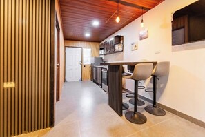 Una cocina con barra, techo de madera y suelo de baldosas.