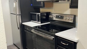 Una cucina con frigorifero, forno a microonde, fornelli, forno e pensili.