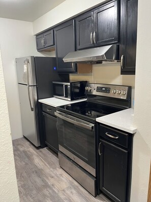 A kitchen with a refrigerator, microwave, stove, oven, and cabinets. -  1-bedroom condo with gas heat (Seattle)
