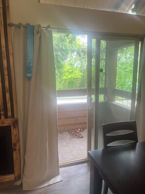 A room with a sliding glass door leading to an outdoor area with a wooden deck and greenery. -  1-bedroom condo with gas heat (Seattle)