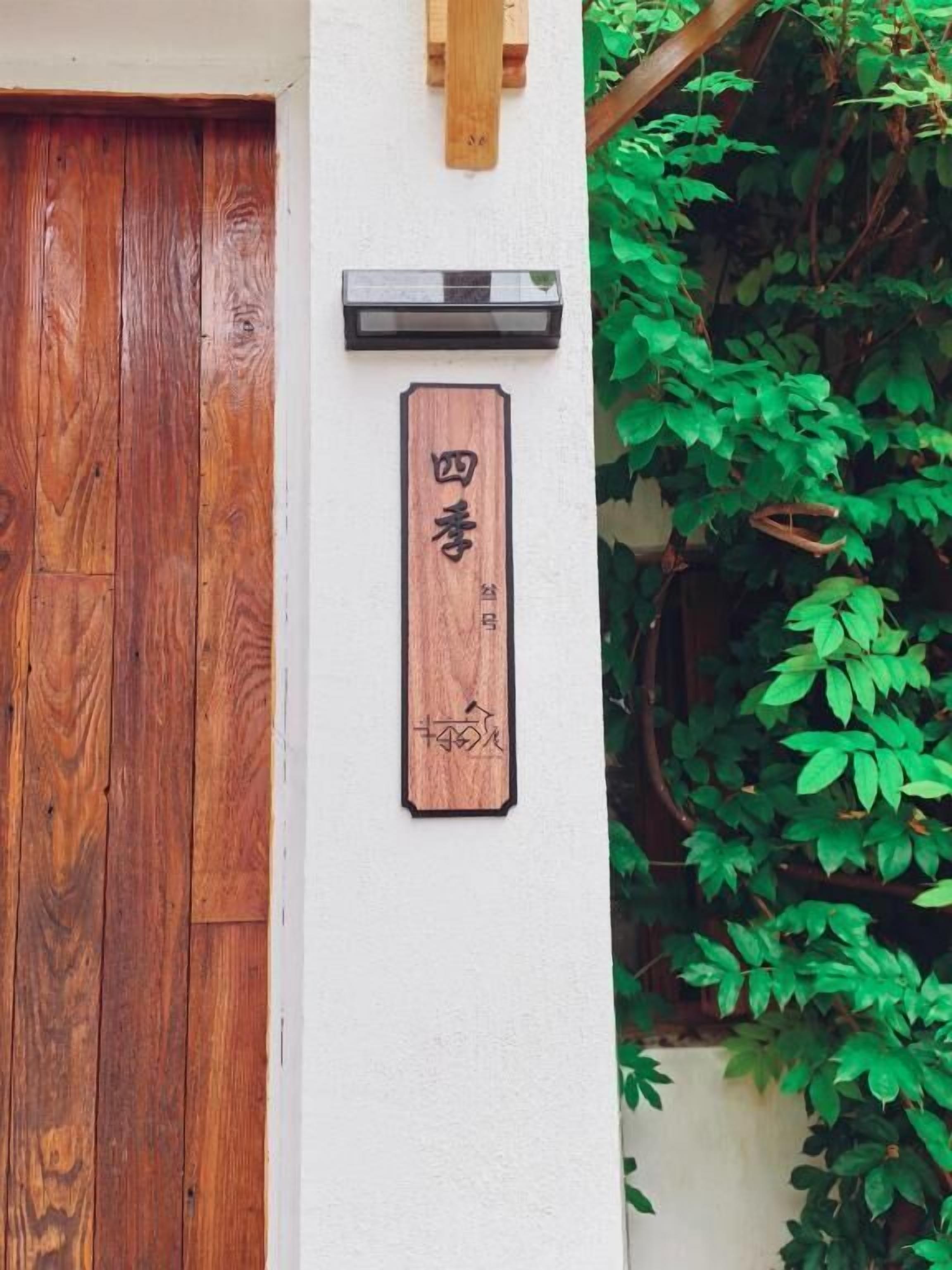 A wooden door, a wall-mounted sign with Chinese characters, and a small mailbox.