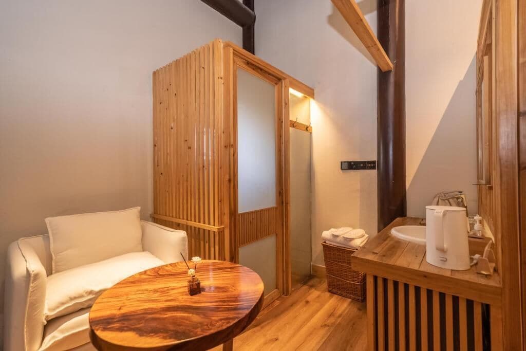 A wooden-framed room with a sofa, a round table, a sink, and a mirror.