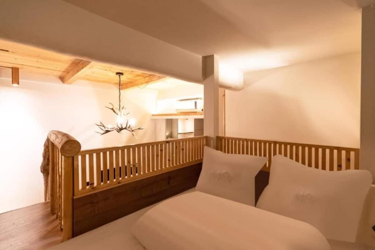 A bedroom with a wooden headboard, a bed with white bedding, and a chandelier.