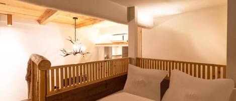 Un dormitorio con cabecera de madera, cama con ropa de cama blanca y un candelabro.