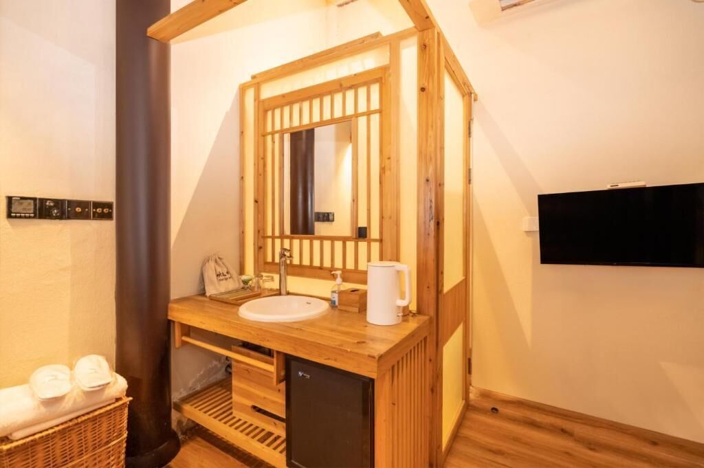 A wooden cabin-style bathroom with a sink, mirror, and a black television mounted on the wall.