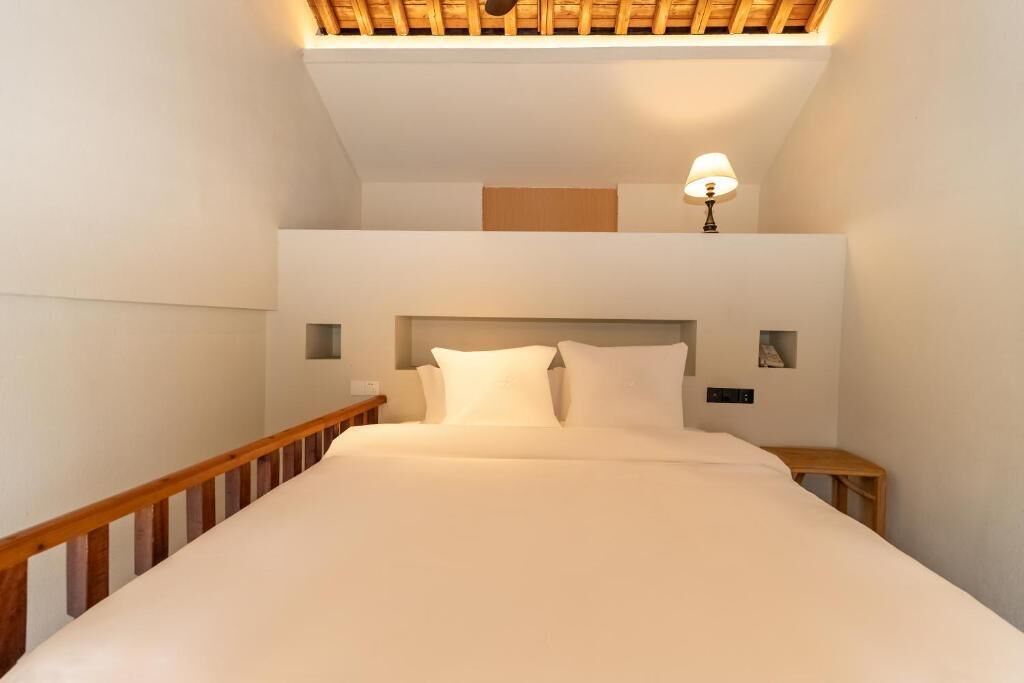 A bedroom with a bed, wooden headboard, bedside tables, and a lamp.