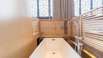 A modern bathroom with a rectangular bathtub, wooden slatted walls, and a window with a geometric pattern.