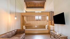 A room with a wooden bench, a sofa, a TV, and a small table with items on it. - Cloud and Wind (Yangzhou)