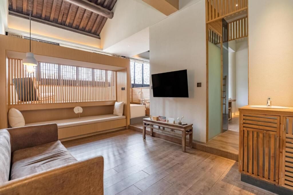 A modern living room with a sofa, a coffee table, a TV mounted on the wall, and a wooden cabinet.