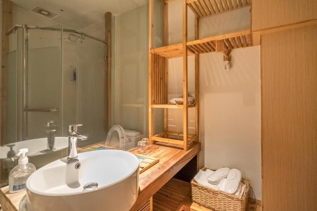 A bathroom with a large sink, a glass shower enclosure, and a wooden vanity with a mirror.